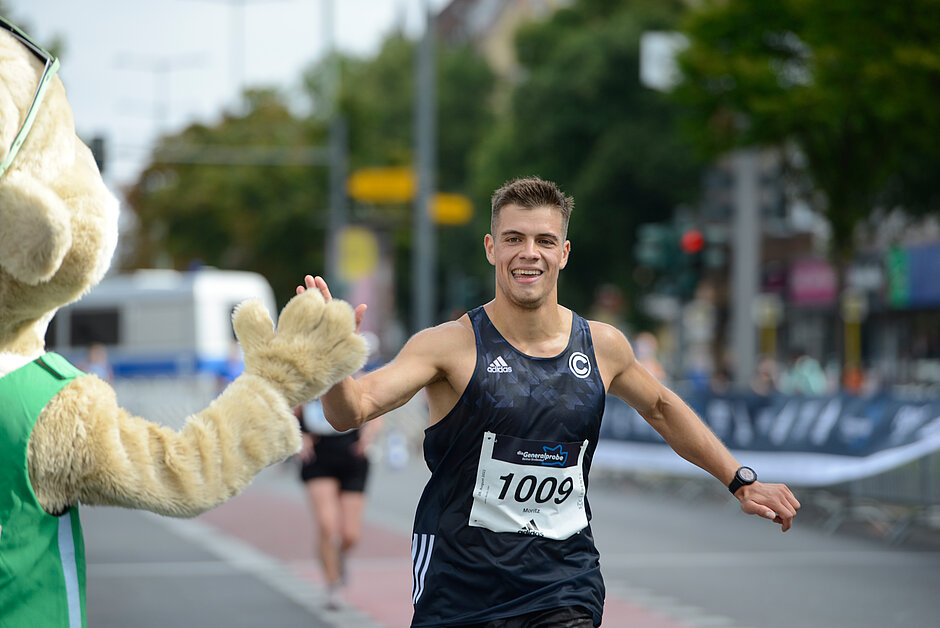 Generalprobe Viertelmarathon (2023): Läufer klatscht Maskottchen Frido Flink ab © SCC EVENTS / Kai Wiechmann