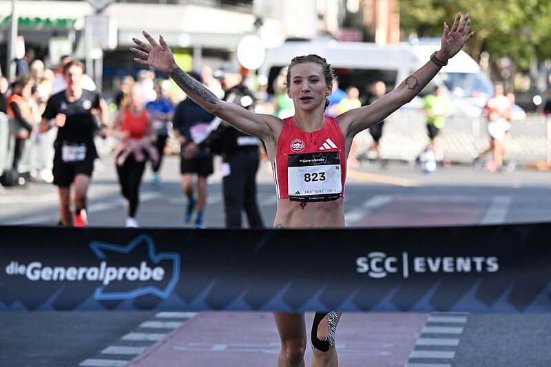 Kristina Händel mit erhobenen Armen kurz vor Durchbrechen des Zielbandes.