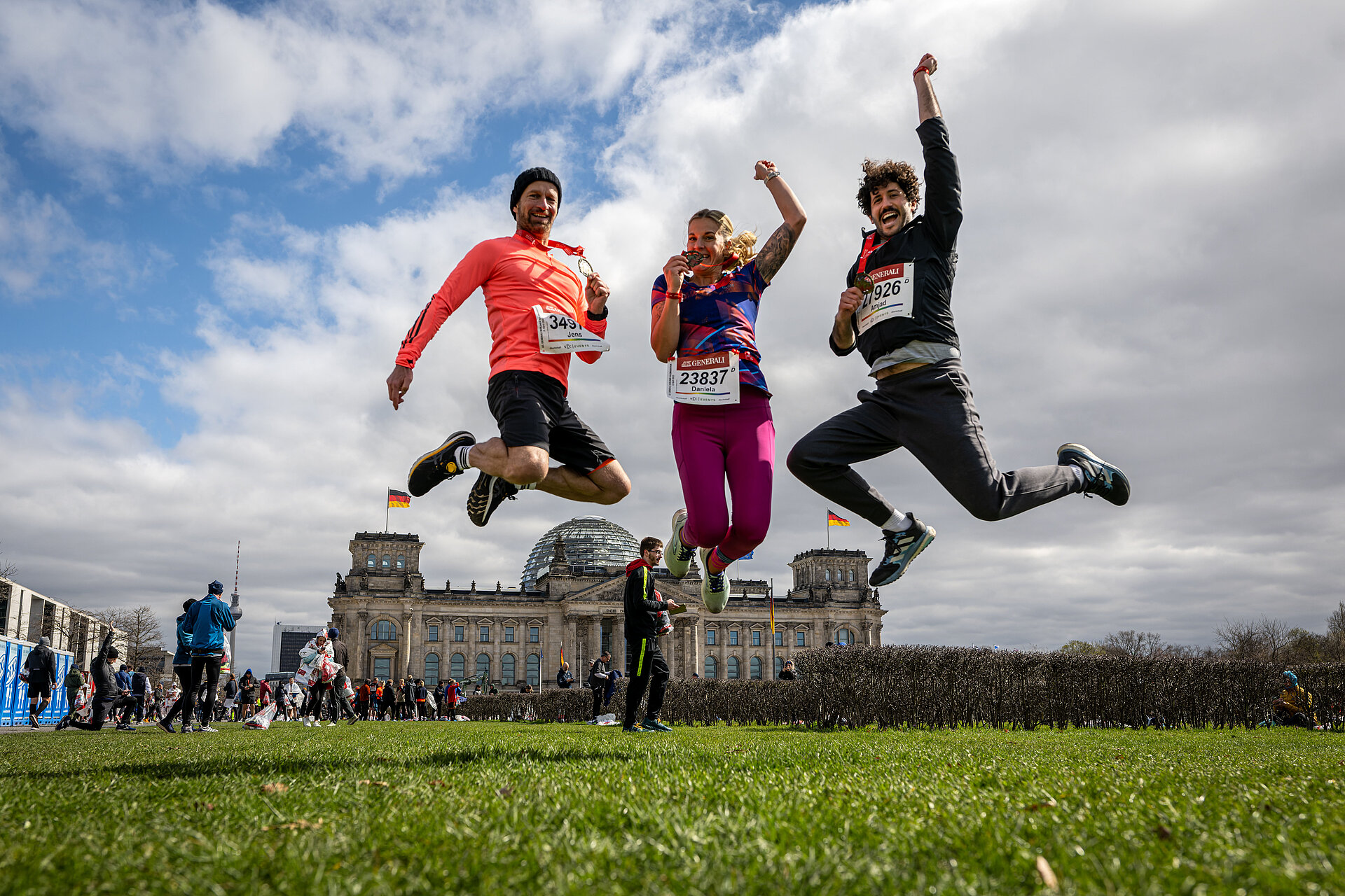 Drei Finisher springen auf der Reichstagswiese in die Luft.